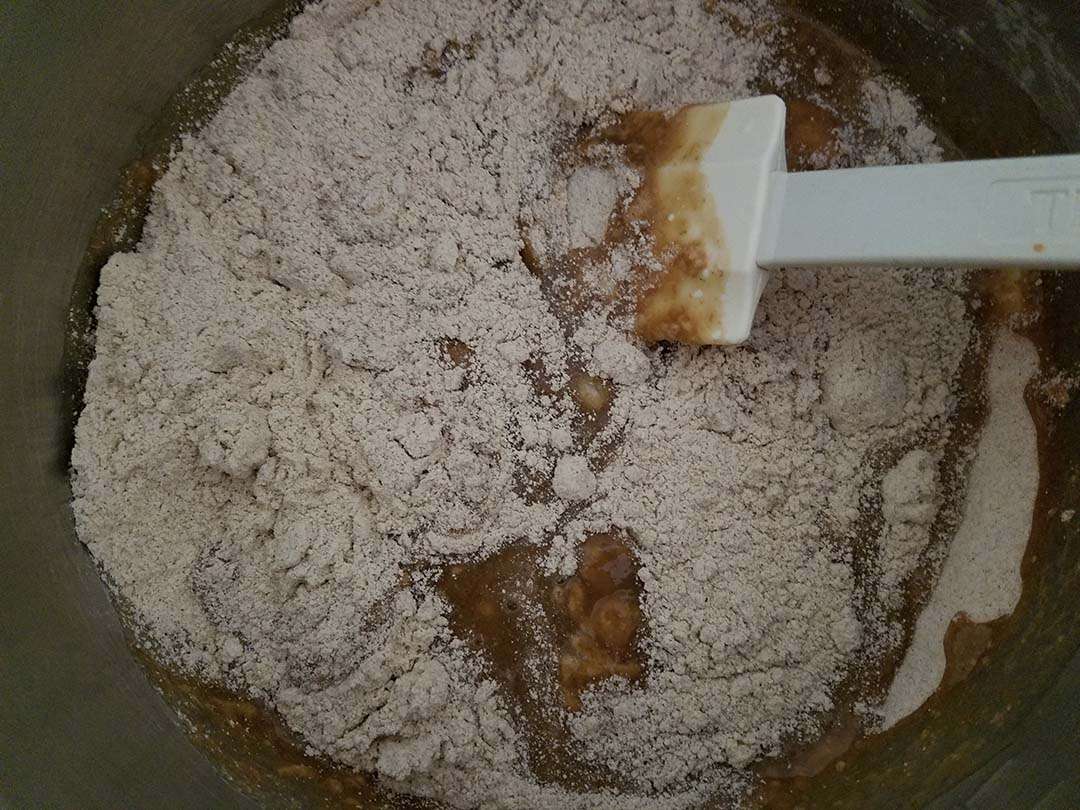 mixing banana mixture with flour for banana bread